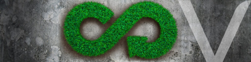 Circular economy symbol covered in grass on a concrete wall, representing sustainability in construction.